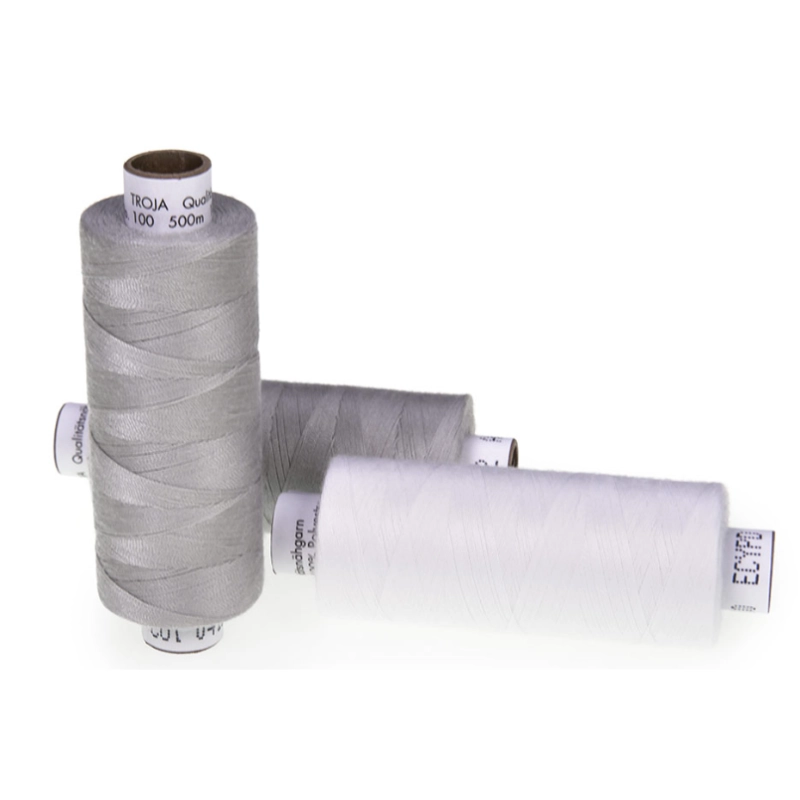 Drei Spulen Nähgarn in verschiedenen Grautönen und Weiß, mit sichtbaren Etiketten.