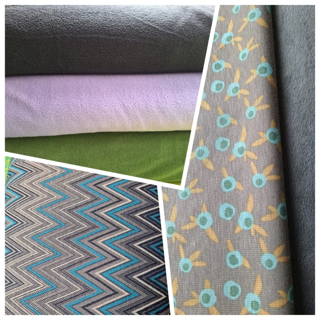 Mehrere Strick- und Fleece-Stoffe in Grau, Lila und Grün sowie gemusterte Stoffe mit türkis-gelben Motiven; 50 % reduziert.
